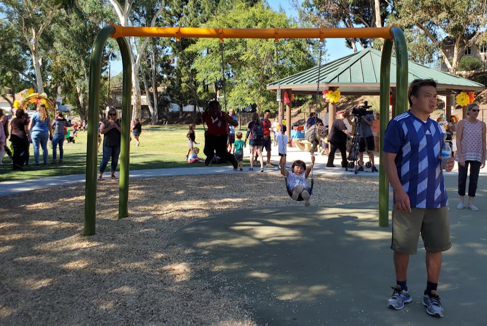 A group of people in the park playing with swings.