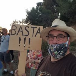 A man holding up a sign that says basta