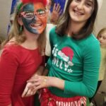 Two girls with face paint and a christmas hat